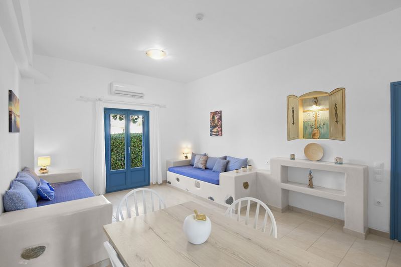 Rose apartment, Flora Apartments Paros – living room with built-in sofas and dining area
